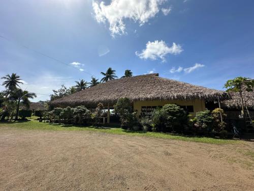 a building with a thatched roof and palm trees at Dancalan Beach Resort in Donsol