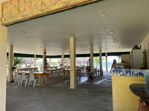 ein Restaurant mit Tischen und Stühlen und eine Person, die an einer Theke sitzt in der Unterkunft Dancalan Beach Resort in Donsol