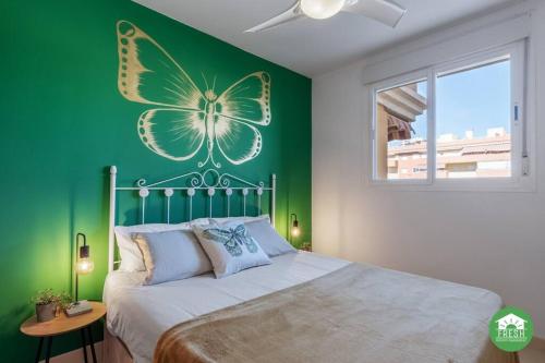 sypialnia z zieloną ścianą z malowidłem motyla w obiekcie Beachfront apartment - terrace with sea view - pool w mieście Algarrobo