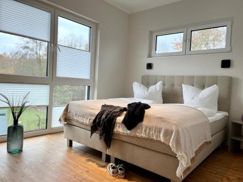 a bedroom with a large bed with four windows at Luxus-Ferienhaus mit Saunen und großem Garten in Göhren-Lebbin
