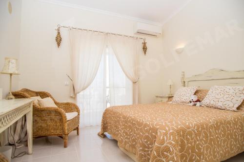 een slaapkamer met een bed, een stoel en een raam bij Vila Golfemar in Carvoeiro
