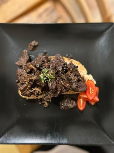 a black plate with a sandwich with meat and tomatoes at Casa Vacanze Le Fornaci in Laterina