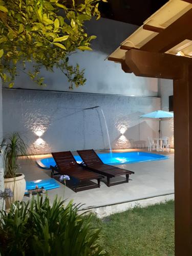 una piscina con 2 sillas y una sombrilla en Casa ÍSIS de aluguel por temporada em Capão da Canoa com piscina en Capão da Canoa