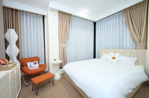 ein Schlafzimmer mit einem weißen Bett und einem Stuhl in der Unterkunft EDEN RESIDENCE in Hanoi
