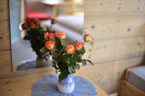 a vase filled with orange roses sitting on a table at Haus Kohler in Häselgehr