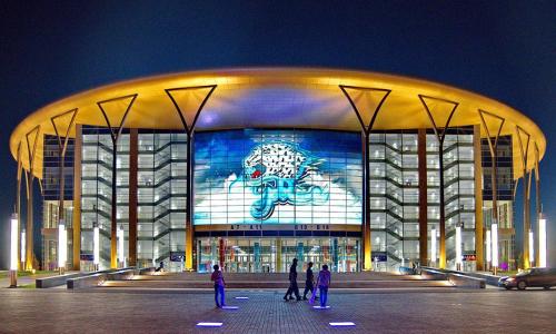 a large building with people standing outside of it at night at ЖК Чемпион in Taldykolʼ