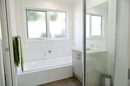 ein weißes Badezimmer mit einer Badewanne und einem Waschbecken in der Unterkunft 7 Gilmore Street, Smiths Beach in Smiths Beach