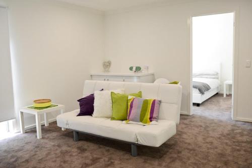 ein Wohnzimmer mit einer weißen Couch mit bunten Kissen in der Unterkunft 7 Gilmore Street, Smiths Beach in Smiths Beach