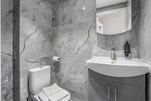 a bathroom with a white toilet and a sink at BeiRoom Hyde Park Apartments in London