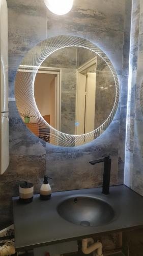 a bathroom with a round mirror over a sink at Vár-i Apartman in Balatonmáriafürdő