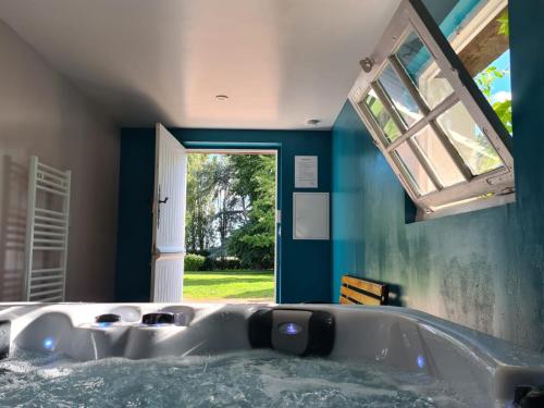 bañera grande en una habitación con ventana en Le Domaine de Baracas - Le Petit Gîte 4 étoiles - SPA - 2 à 4 personnes en Huisseau-sur-Mauves