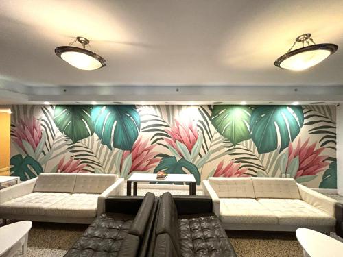 a lobby with couches and a mural of plants at Collins Hotel in Miami Beach