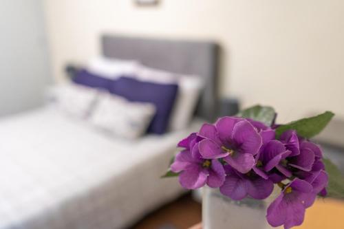 una flor púrpura en un jarrón blanco sobre una mesa en Coliving Med by Hotel Mediterràneo en Montevideo