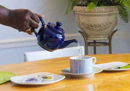 a person pouring coffee into a blue tea pot on a table at Arawak Bay: Inn at Salt River in Christiansted