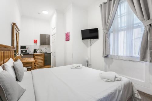 a white bedroom with a white bed and a television at BeiRoom Hyde Park Apartments in London