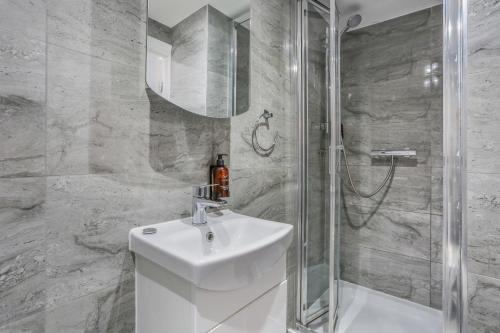 a white bathroom with a sink and a shower at BeiRoom Hyde Park Apartments in London