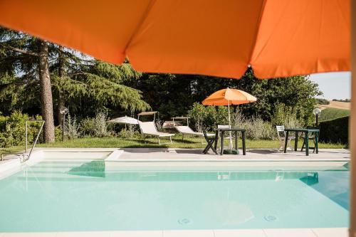 a pool with two tables and an orange umbrella at B&B Timeout in Polverigi