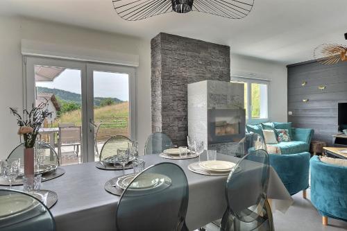 a living room with a table with chairs and a fireplace at Gîte Les Libellules - 12 personnes - 4 étoiles - Spa in Fresse-sur-Moselle