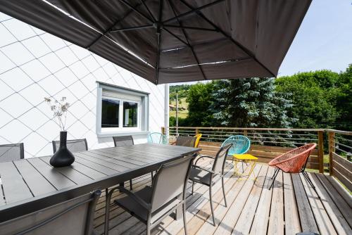 a table and chairs on a deck with an umbrella at Gîte Les Libellules - 12 personnes - 4 étoiles - Spa in Fresse-sur-Moselle