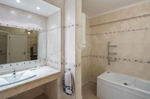 a bathroom with a sink and a tub and a mirror at Maio Apartment in Luz