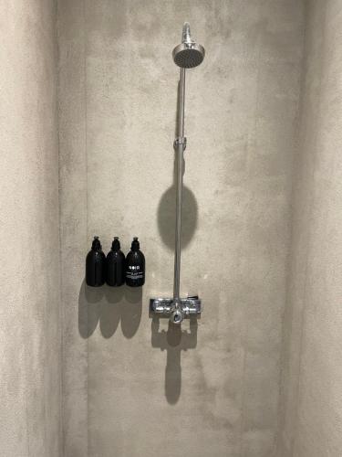 a shower with three black bottles on the wall at Chambre hotell in Stockholm