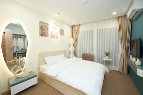 a bedroom with a white bed and a television at EDEN RESIDENCE in Hanoi