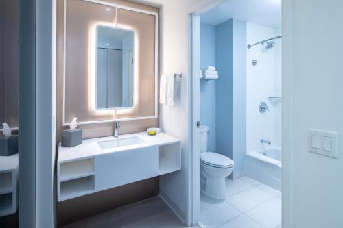 ein Badezimmer mit einem Waschbecken, einem WC und einem Spiegel in der Unterkunft Universal's Stella Nova Resort in Orlando