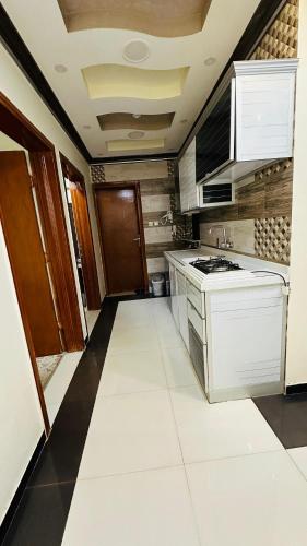 La cuisine est équipée de placards blancs et d'un four avec plaques de cuisson. dans l'établissement أجنحة بلو روز الفندقية, à Najran