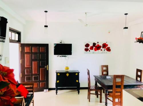 a living room with a dining room table and a television at Nasareth Villa Unawatuna in Galle