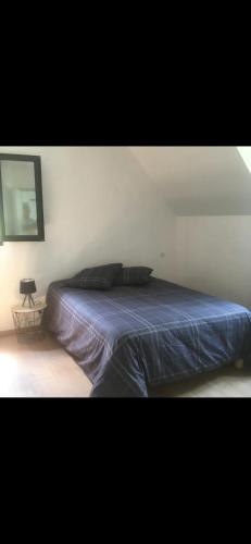 een bed in een slaapkamer met een blauw dekbed bij Maison récente très spacieuse in Forges-les-Bains