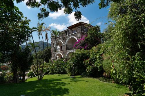 an old stone house in a garden with palm trees at Posada del Tepozteco - Hotel & Gallery in Tepoztlán