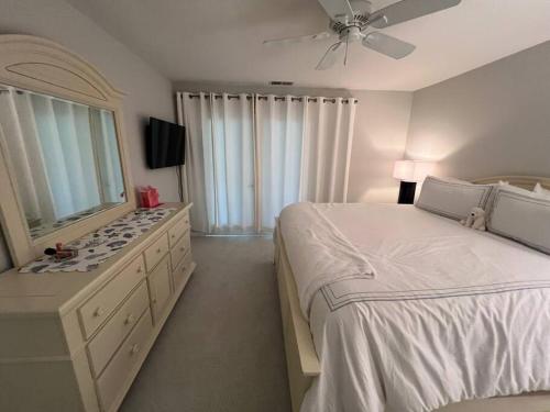 a white bedroom with a large bed and a dresser at Palmetto Breeze, Golf Course New furniture, carpet in Johns Island