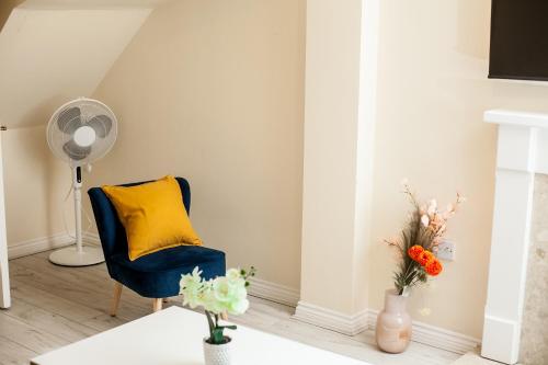 een woonkamer met een blauwe stoel en een geel kussen bij Avril Warwickshire Home Stay in Nuneaton