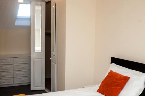 a bedroom with a bed with a red pillow on it at Avril Warwickshire Home Stay in Nuneaton
