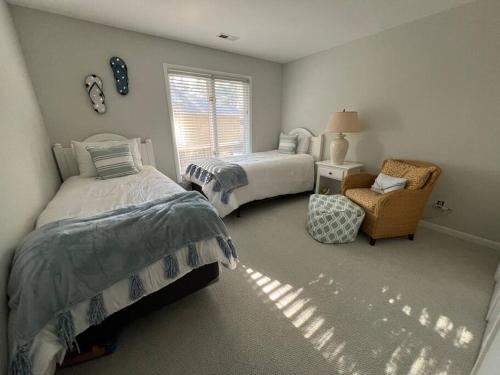 a bedroom with two beds and a chair and a window at Palmetto Breeze, Golf Course New furniture, carpet in Johns Island