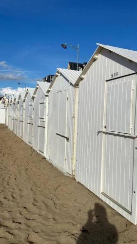 un ours en peluche debout devant une rangée de bâtiments dans l'établissement Le Studio 21 Carlotta, à Villers-sur-Mer