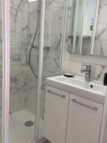 une salle de bain blanche avec une douche et un lavabo dans l'établissement Le Studio 21 Carlotta, à Villers-sur-Mer