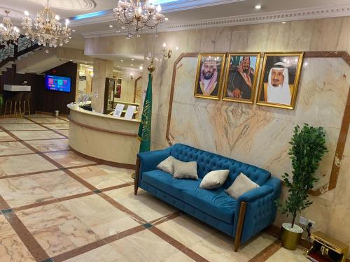 a blue couch in a lobby with pictures on the wall at زهرة الميناء للشقق المخدومة in Jeddah