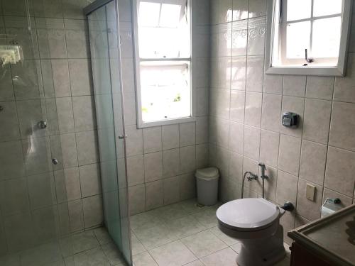 a bathroom with a shower and a toilet and a window at Pousada Sossego in São Gabriel