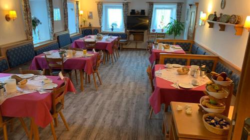 una sala da pranzo con tavoli con tovaglia rossa di Pension Gregory a Schönau am Königssee