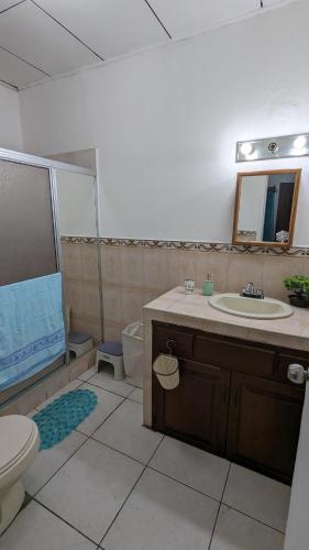 a bathroom with a sink and a toilet and a mirror at La casa de don Matilde in San Pedro Sula