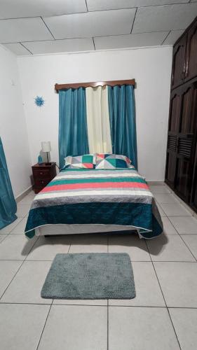 a bedroom with a bed with blue curtains and a rug at La casa de don Matilde in San Pedro Sula
