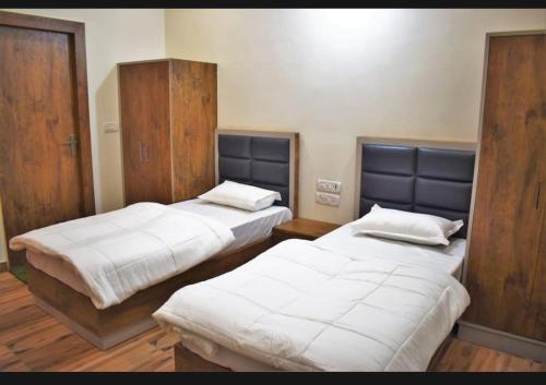 two beds in a room with wooden floors at Moms Hostel in Agra