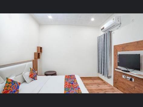 Schlafzimmer mit einem Bett und einem Flachbild-TV in der Unterkunft Moms Hostel in Agra