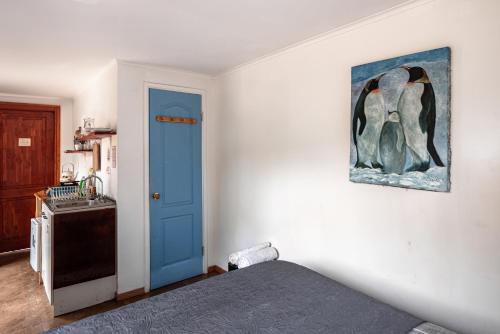 a bedroom with a blue door and a picture of a penguin at Cabañitas del Bosque in Algarrobo