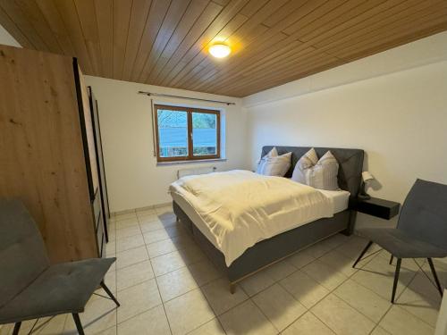 una camera da letto con un letto con due sedie e una finestra di Ferienwohnung Supp a Zweibrücken