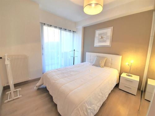 a bedroom with a white bed and a window at Parc Imperial by Welcome to Cannes in Cannes