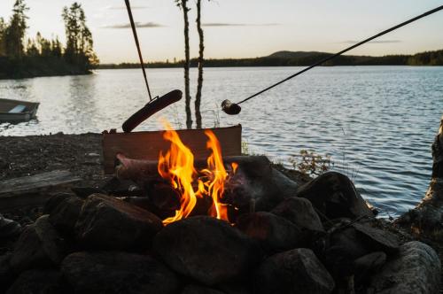a campfire on the shore of a lake at Vikinggård Cottages in Höljes