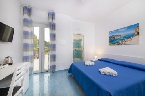 - une chambre avec un lit bleu et des serviettes dans l'établissement B&B La Vigna Rooms - Ischia Ponte, à Ischia