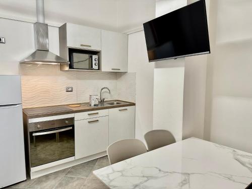 uma cozinha com armários brancos e uma mesa com cadeiras em Residence Rimini Relax em Rimini